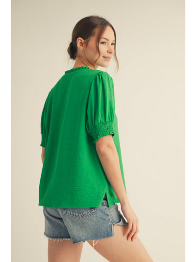 Woman wearing a green blouse and denim shorts on a beige background