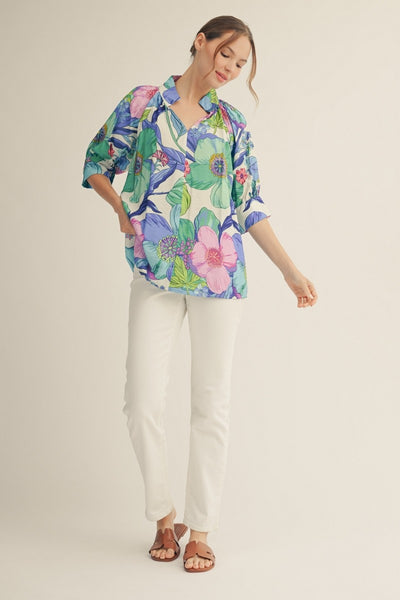 model wearing a blue floral top & white pants