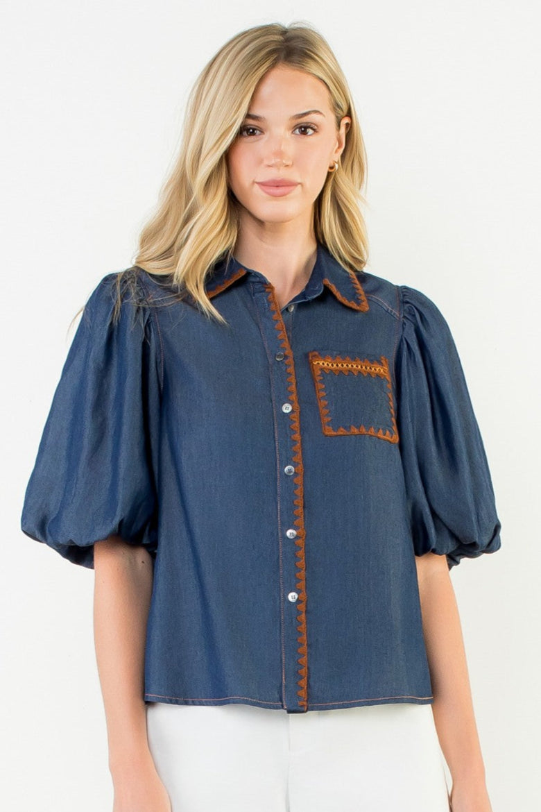 Woman wearing a blue blouse with brown accents on a white background