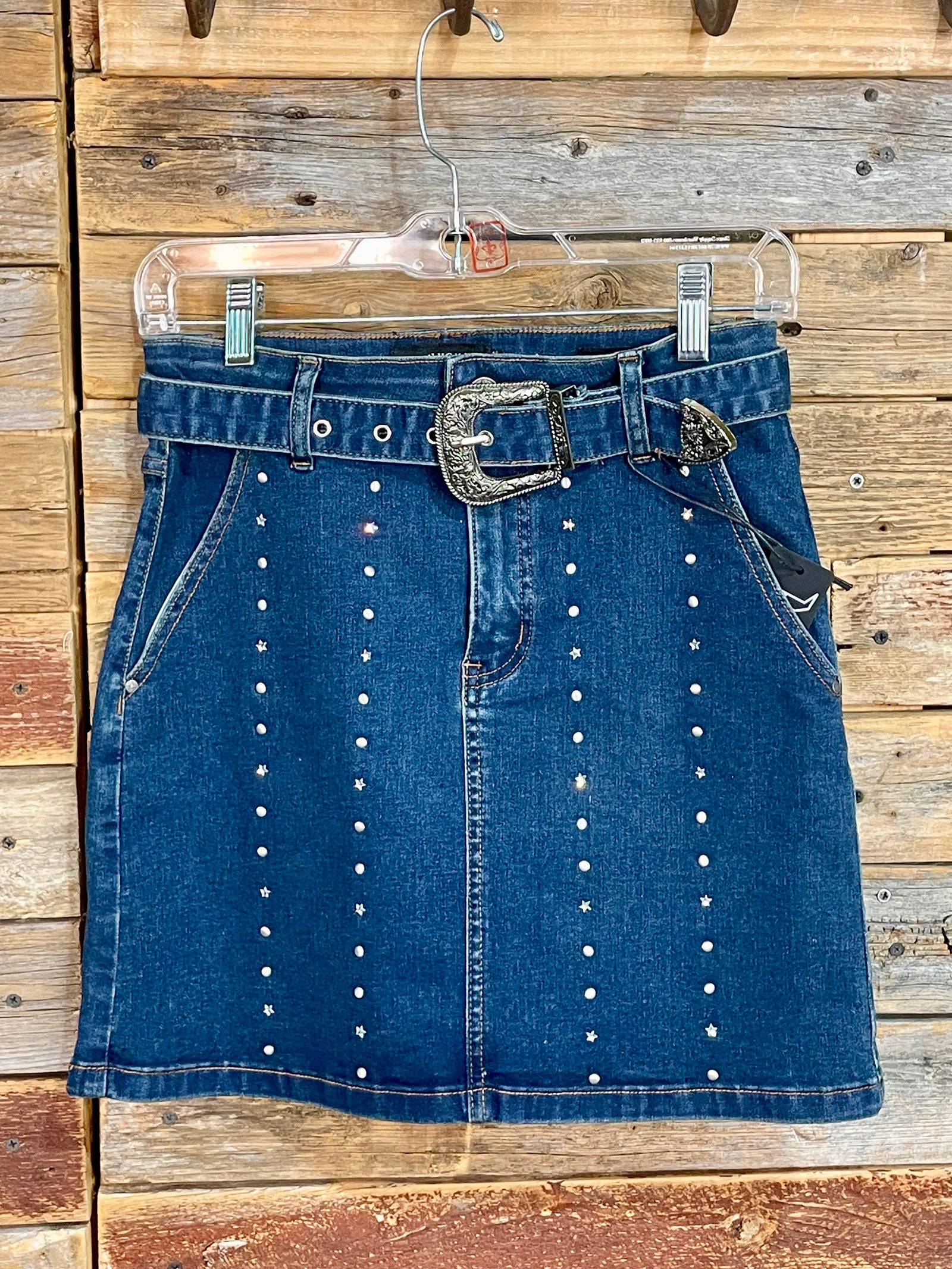 Blue denim skirt with decorative buttons and a belt on a wooden background