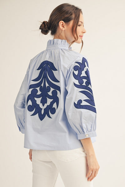 model wearing a blue Applique blouse & white pants