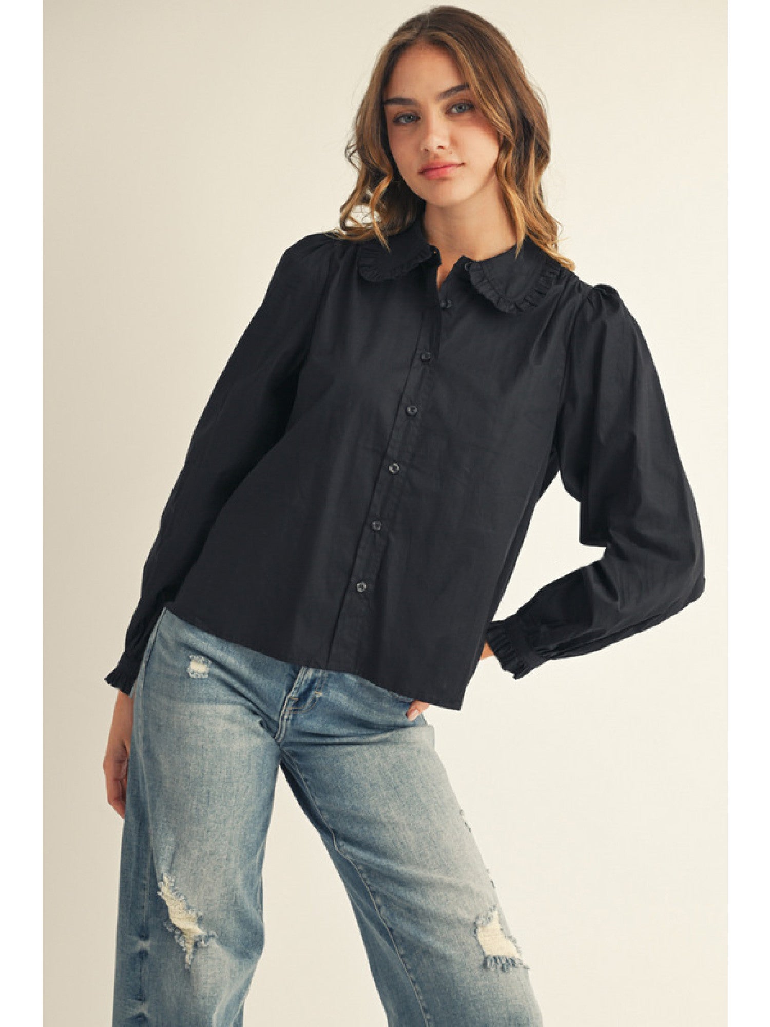 Woman wearing a black shirt and blue jeans on a plain background