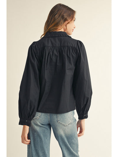 Person wearing a black long-sleeve shirt and blue jeans on a beige background