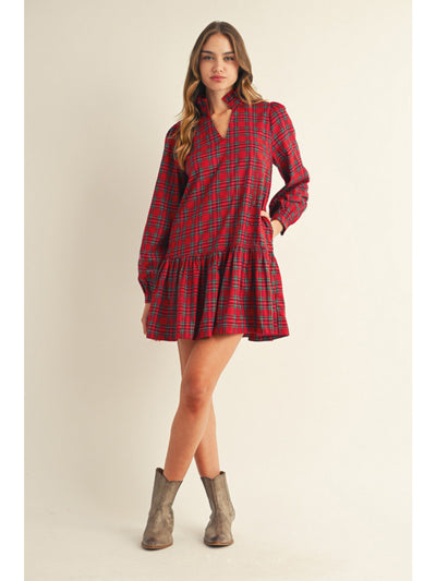 Woman wearing a red plaid dress with long sleeves on a beige background