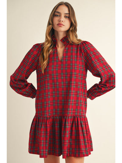 Woman wearing a red plaid dress against a beige background