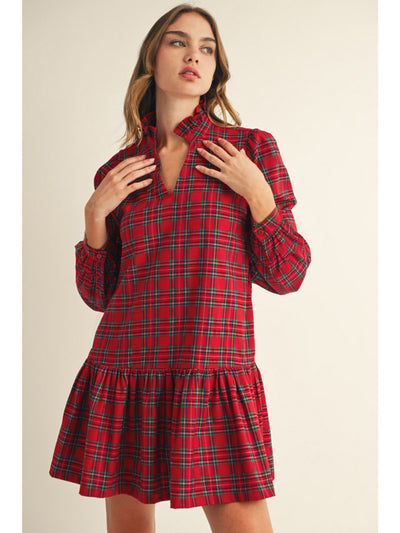 Woman wearing a red plaid dress against a beige background