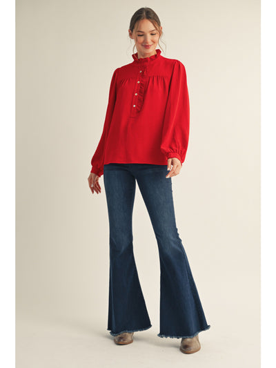 Woman wearing a red blouse and blue flared jeans on a beige background