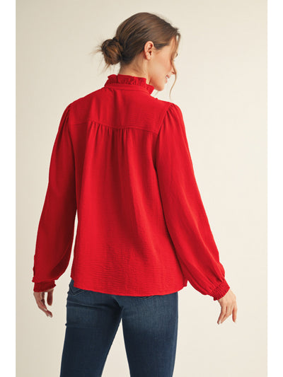 Woman wearing a red blouse with long sleeves on a beige background