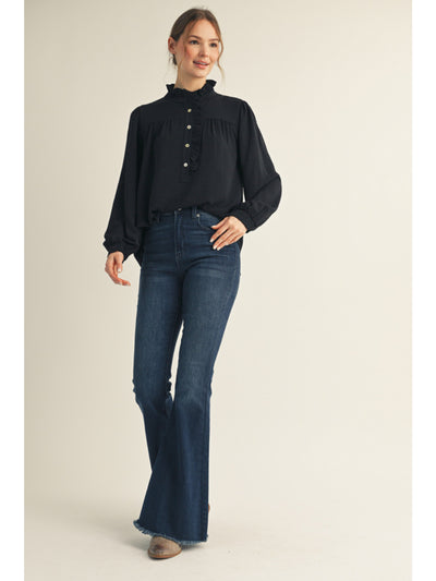 Woman wearing a black blouse and blue jeans on a beige background