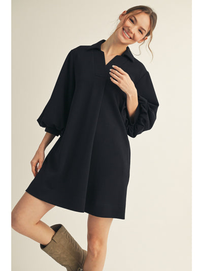 Woman wearing a black dress with long sleeves on a beige background