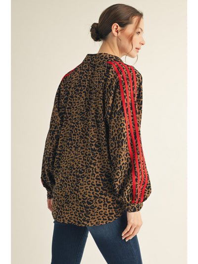 Woman wearing a leopard print shirt with red stripes on a beige background