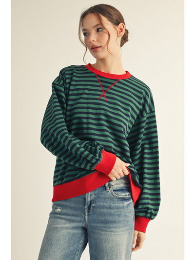 Person wearing a green and red striped sweater with a plain background