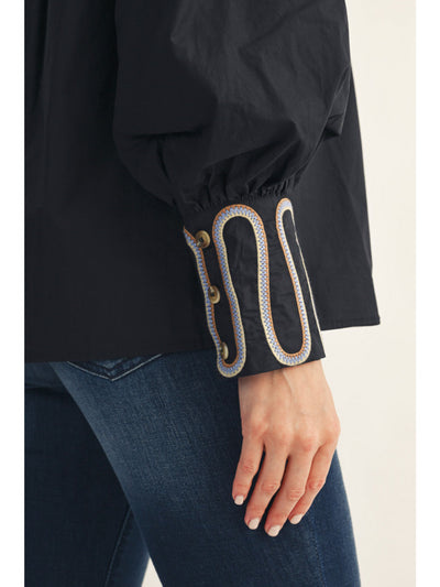 Black jacket with decorative cuffs on a neutral background