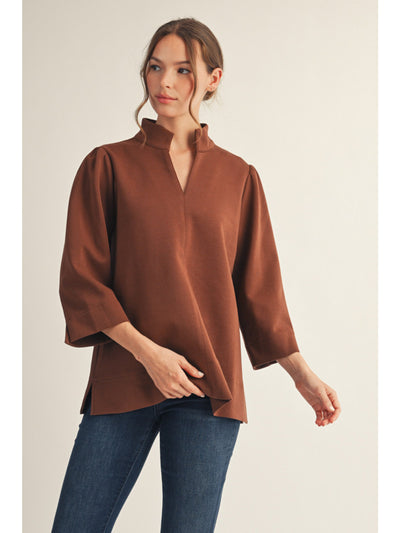 Woman wearing a brown blouse and blue jeans on a beige background