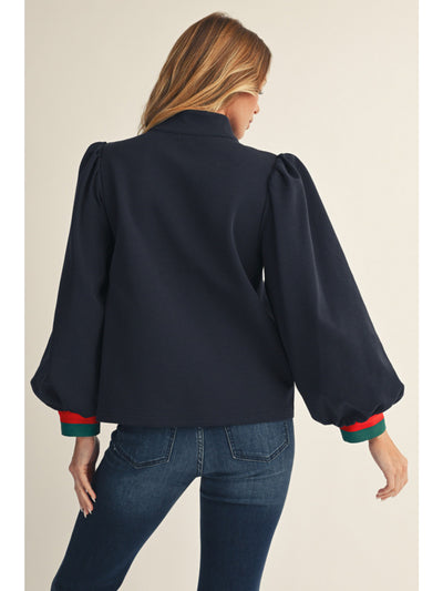 Woman wearing a navy blue blouse with puff sleeves on a beige background