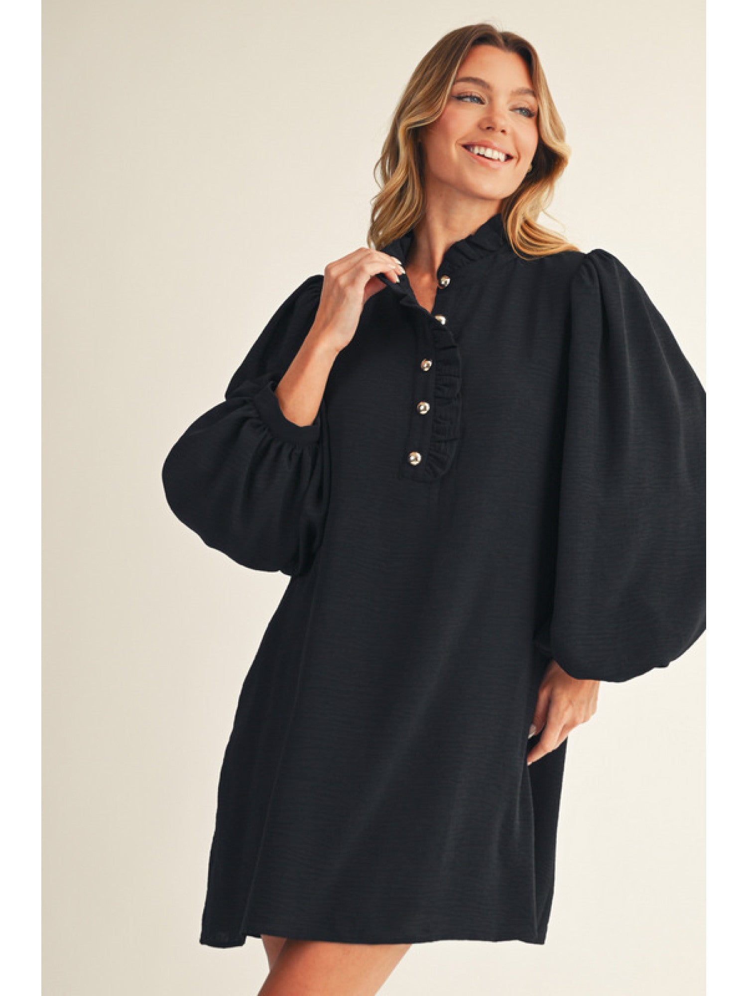 Woman wearing a black dress with puffed sleeves on a plain background