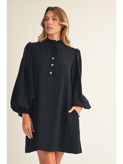 Woman wearing a black dress with puff sleeves on a beige background