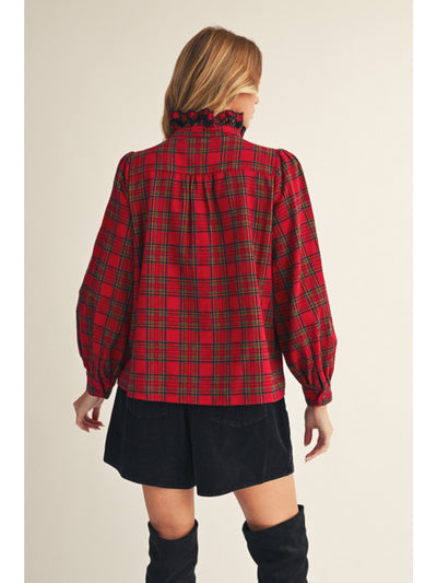 Person wearing a red plaid shirt with a high collar on a beige background