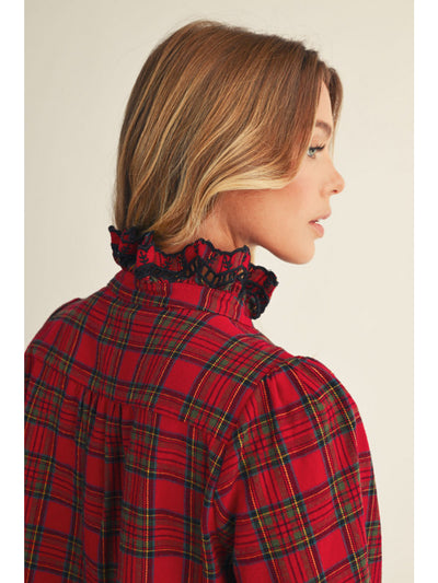 Person wearing a red plaid shirt with a decorative collar against a beige background