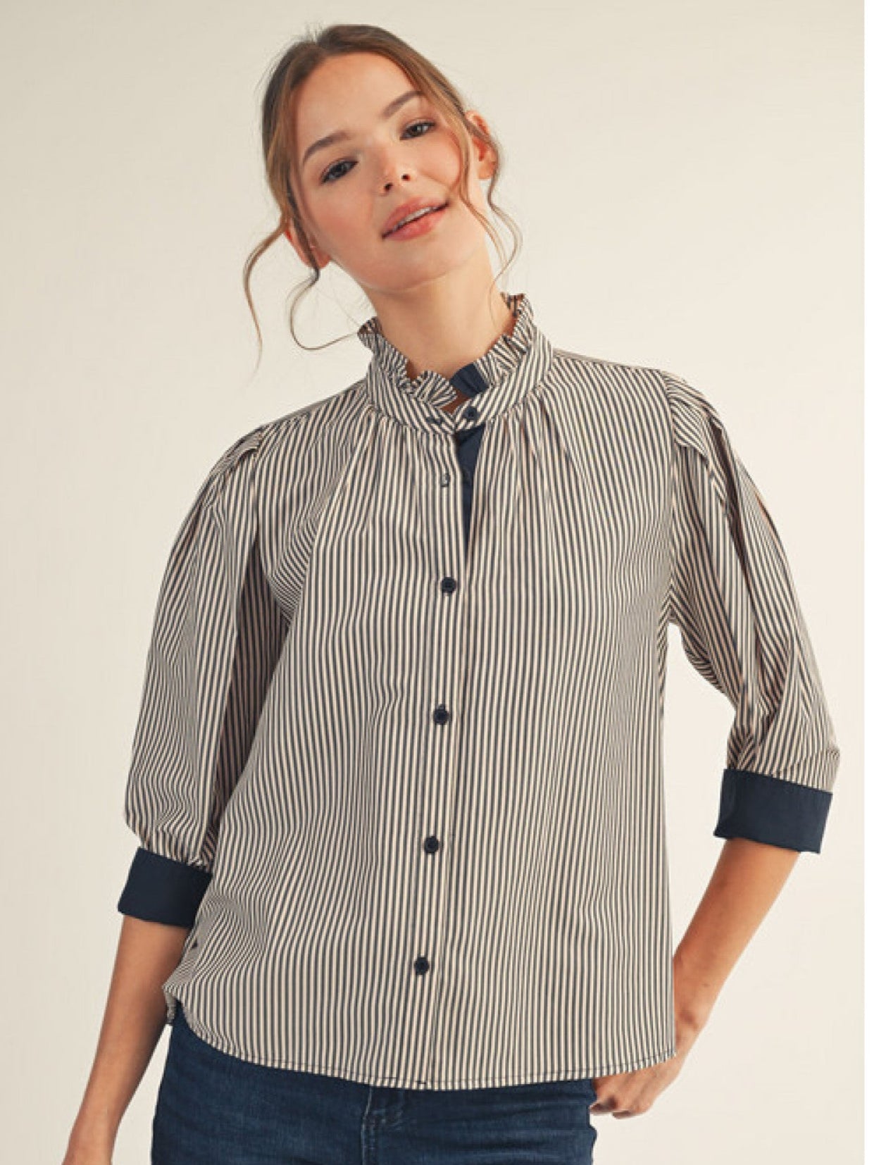 Woman wearing a striped shirt with rolled-up sleeves on a plain background