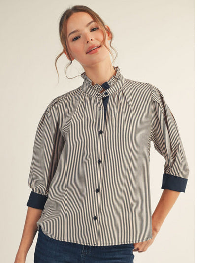 Woman wearing a striped shirt with rolled-up sleeves on a plain background