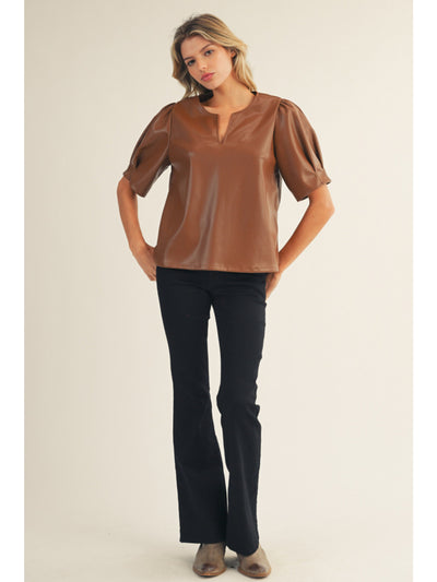 Woman wearing a brown blouse and black pants on a beige background