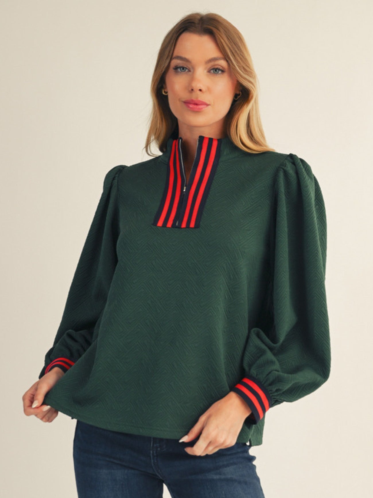 Woman wearing a green blouse with red accents on a plain background