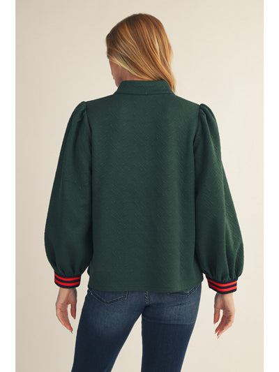 Person wearing a green blouse with puffed sleeves on a beige background