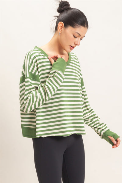 model wearing a green striped sweater and black pants with a light background