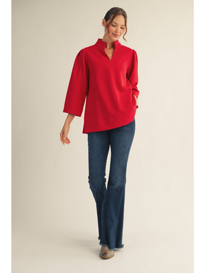 Woman wearing a red blouse and blue jeans on a beige background