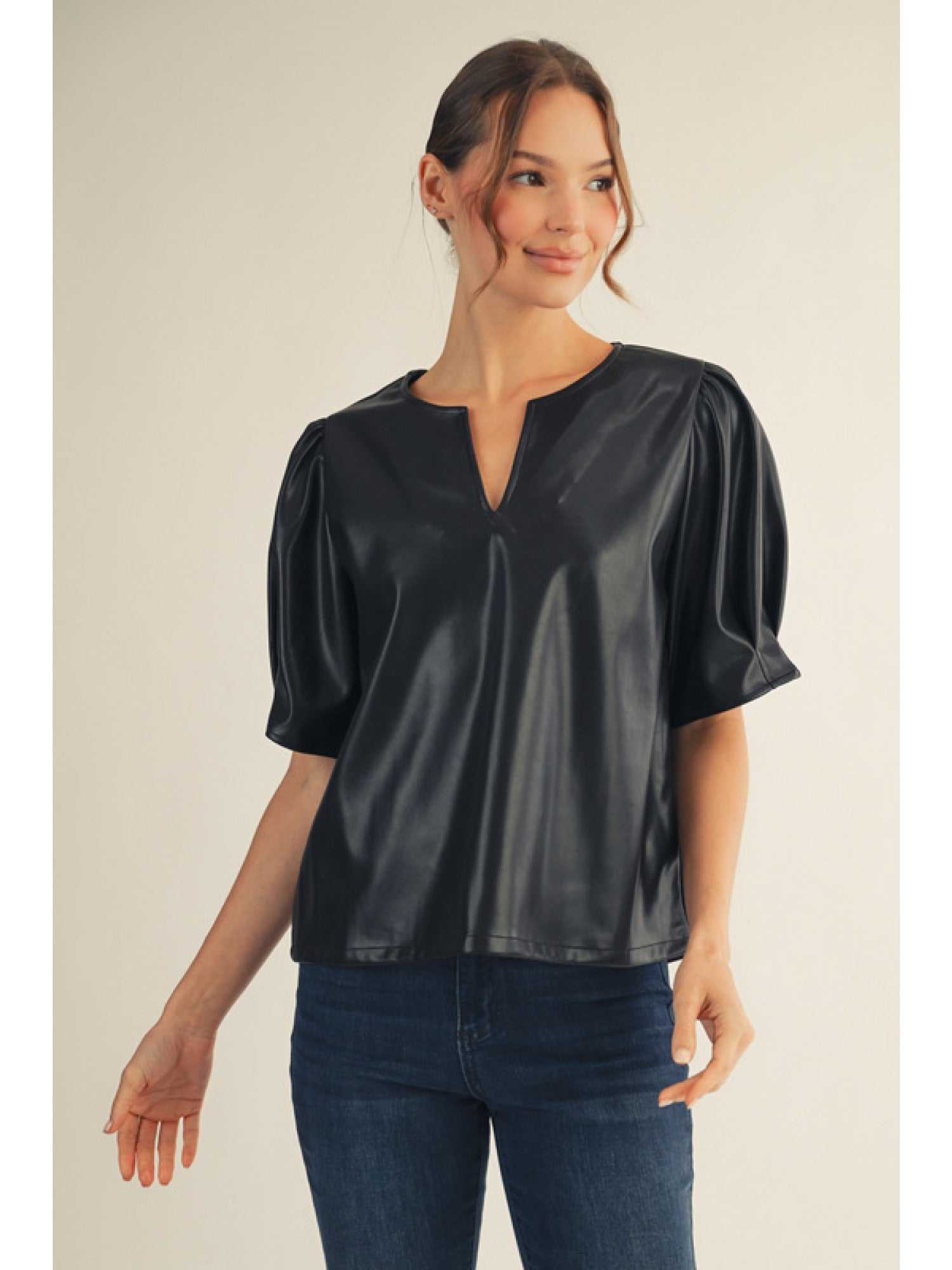 Woman wearing a black satin blouse and blue jeans on a plain background