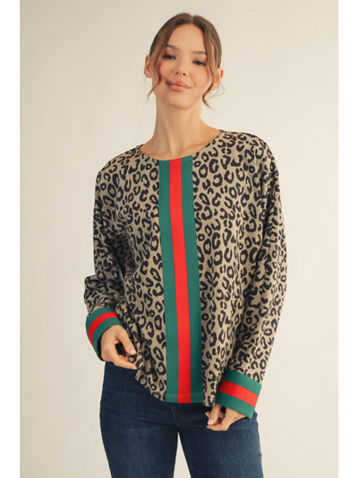 Woman wearing a leopard print sweater with green and red stripes on a plain background