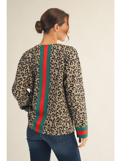 Woman wearing a leopard print top with red and green stripes on a beige background