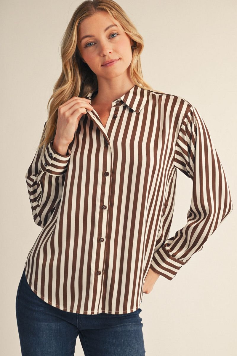 model wearing a brown striped top with jeans before a beige background