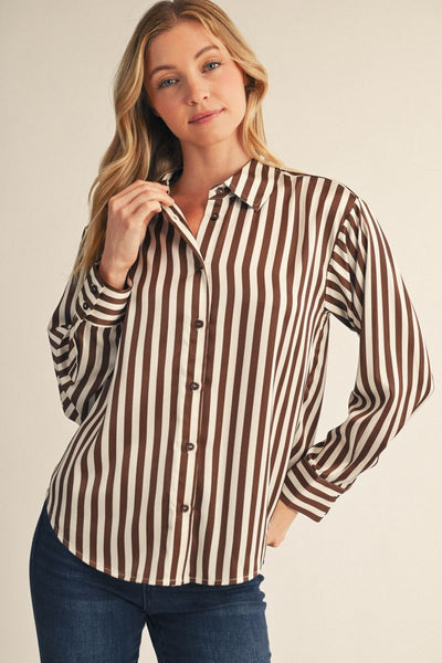 model wearing a brown striped top with jeans before a beige background