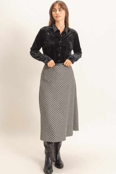 model wearing a black top and black checkered skirt with a light background