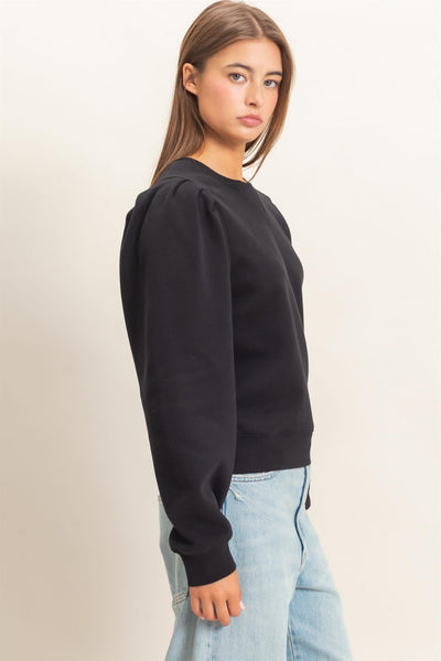 model wearing black top and jeans in front of a light background