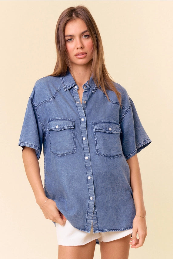 model wearing a short sleeve denim top & white shorts with a tan background