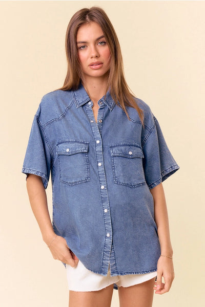 model wearing a short sleeve denim top & white shorts with a tan background