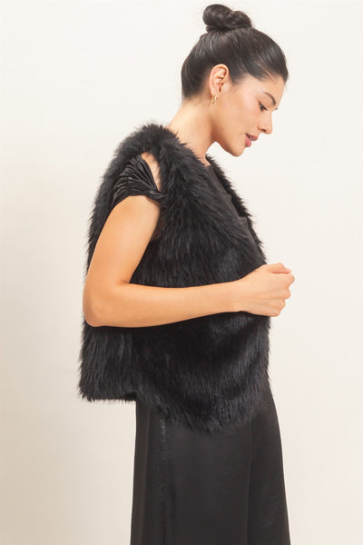 model wearing a black satin outfit & black faux fur vest with a light background