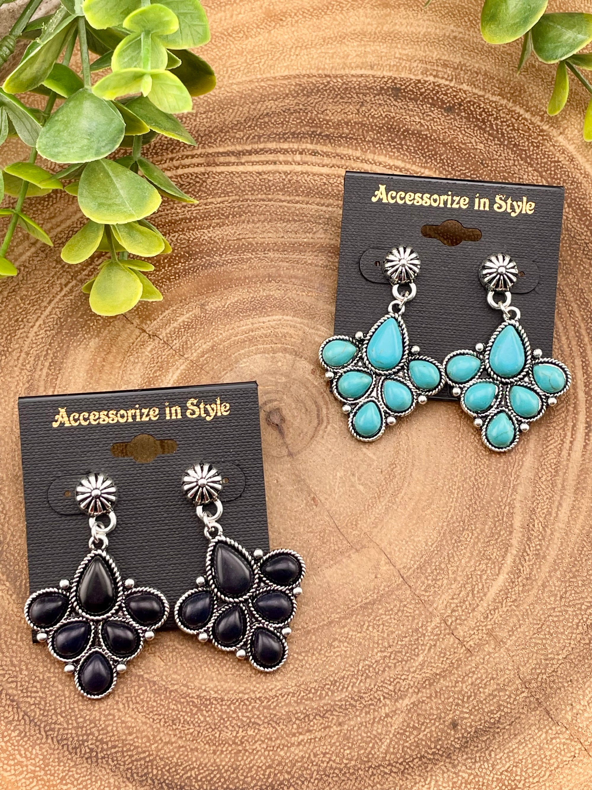Pair of earrings on 'Accessorize in Style' cards with green leaves in the background