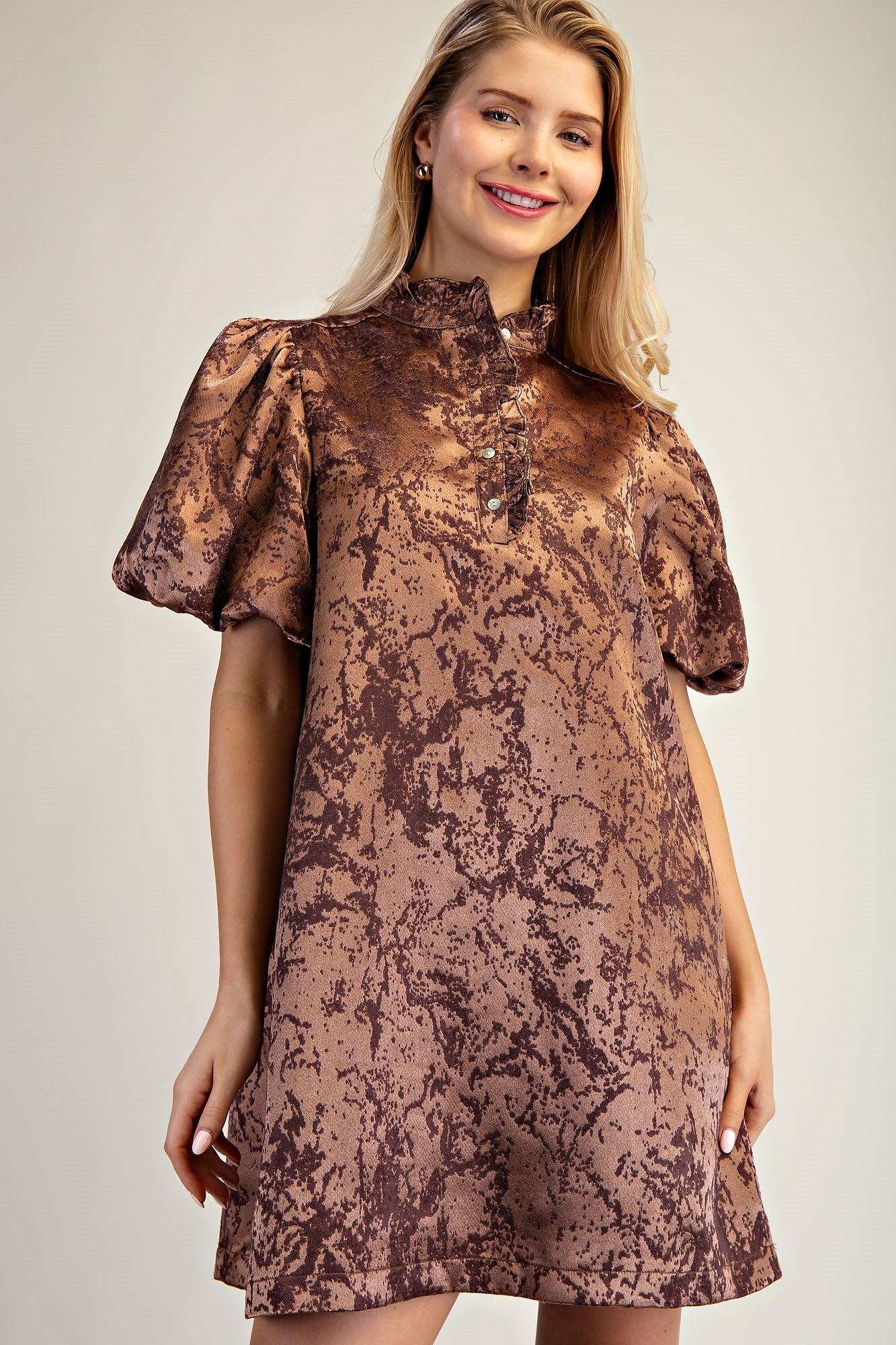 Woman wearing a brown patterned dress against a plain background