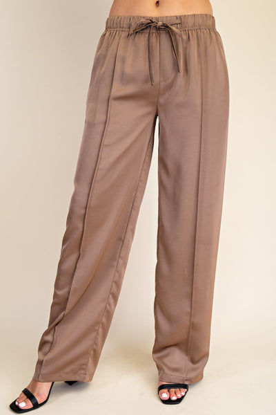 Brown satin pants on a beige background