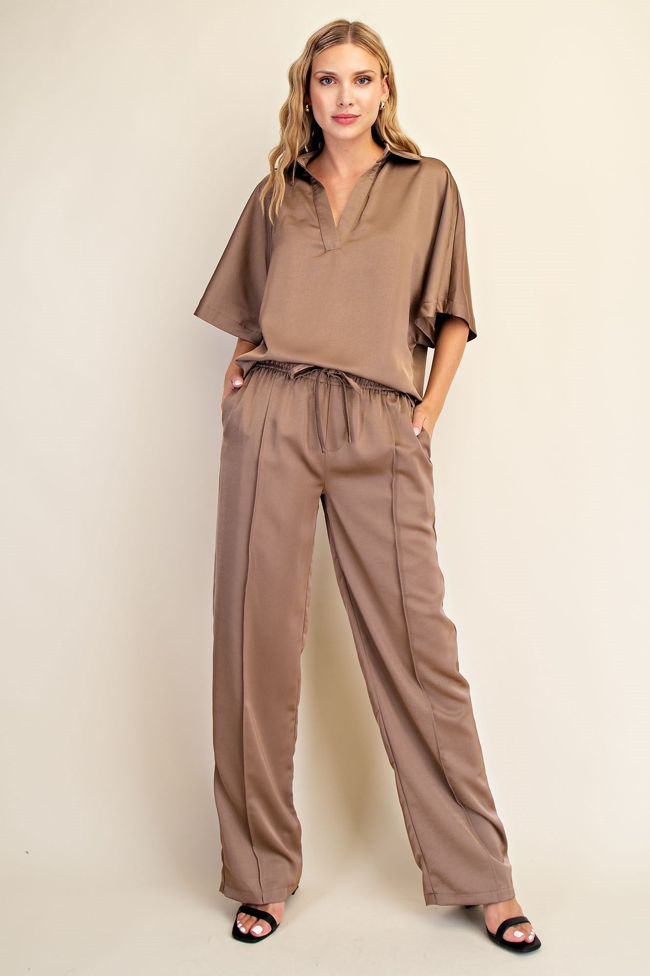Woman wearing a brown outfit against a beige background