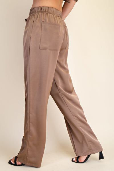 Brown wide-leg pants worn by a person on a beige background
