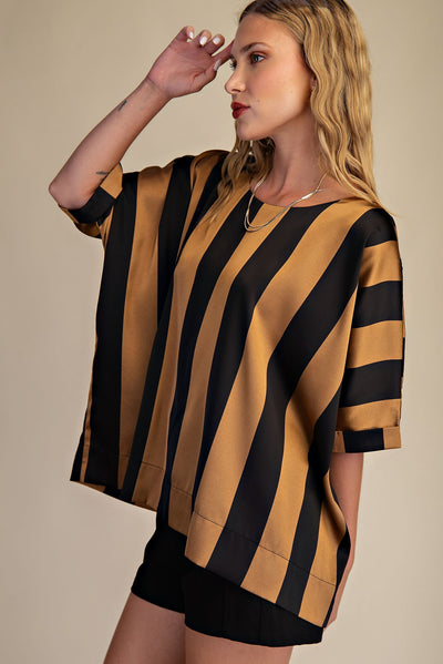 Woman wearing a black and mustard striped shirt against a beige background