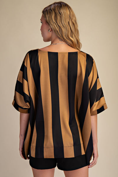 Woman wearing a black and gold striped shirt with a beige background