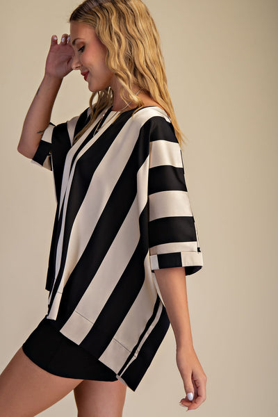 Woman wearing a black and white striped dress against a beige background