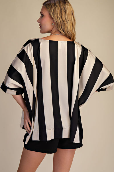 Woman wearing a black and white striped top with a plain background
