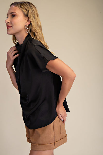 Woman wearing a black top and brown shorts on a beige background